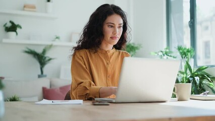 Video of beautiful business woman working with laptop in living room at home. - Powered by Adobe