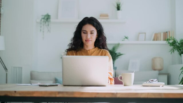 Video of beautiful business woman working with laptop in living room at home.