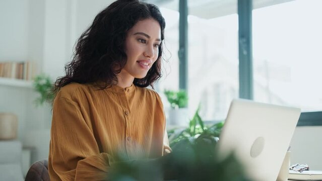 Video of beautiful business woman working with laptop in living room at home.