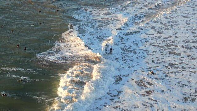 Aerial drone shot of surfers at Ereaga beach at sunset near the shore, Getxo, Spain