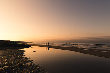 Fototapeta premium Couple se promenant sur la plage au coucher du soleil