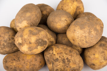 Stack of unwashed potatoes on a white background