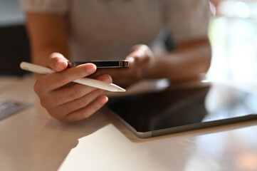 Asian female freelancer remote working at the co-working space using her smartphone and tablet