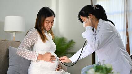 Asian female doctor or obstetrician listening baby's heartbeat by her stethoscope.