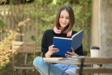 Obraz premium Pleasant young woman relaxing outdoor and reading book, enjoy spending winter holiday