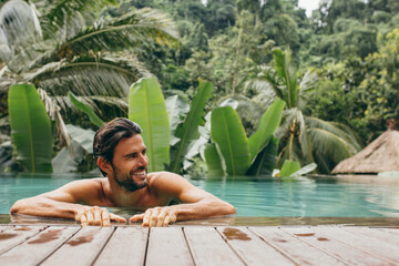 Man in pool at luxury holiday resort - Powered by Adobe