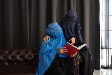 Asian women with burka reading the Islamic Quran