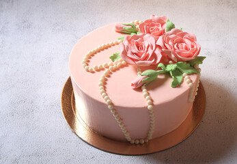 Beautiful dessert festive pink cream cake with roses on a light gray background