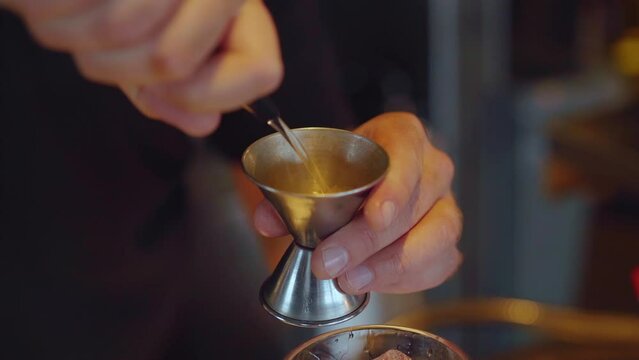 Bartender using jigger to create some cocktail in bar. Slow motion.