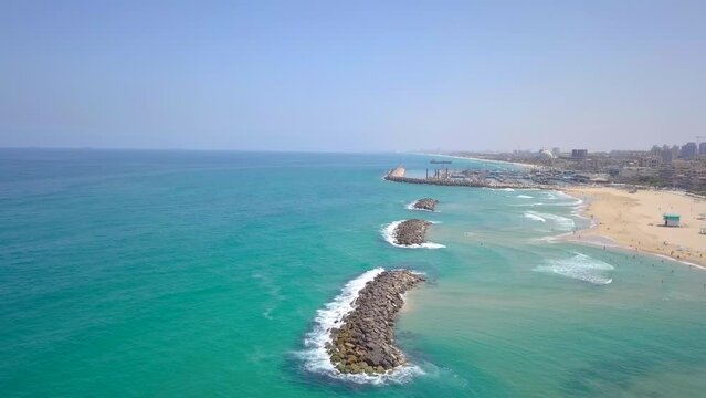 Sunny Summer Aerial in Israel, Ashkelon Beach - Pan from the Ocean over rock dams to the city