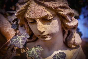 Sad angel as symbol of pain, fear and end of life. Close up fragment of an ancient stone statue.  Horizontal image.