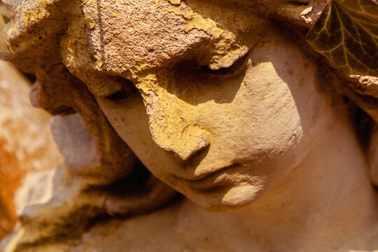 Face of sad beautifuul angel as symbol of pain, fear and end of life. Close up fragment of an ancient stone statue.