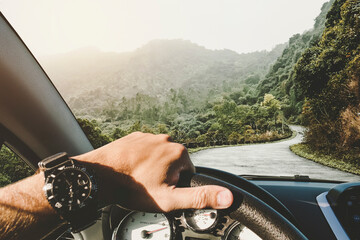 Driving a car on mountain road. View of mountains through windscreen. A man rides on a mountain...