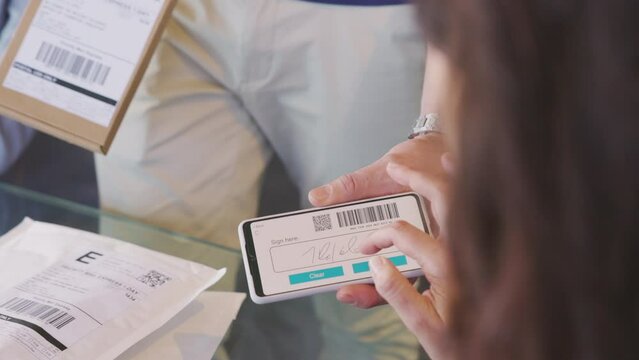 Woman signing delivery receipt on smart phone device