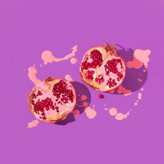 Romantic creative layout with paint spilled over pomegranate halfs  on bright purple background....