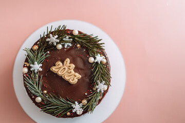 Chocolate cake decorated with Christmas tree branches and numbers 2023.