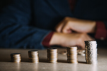 saving money hand putting coins on stack on table with sunshine. concept finance and accounting