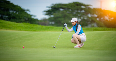 Woman golfer check line for putting golf ball on green grass ,player crouching and study the green...