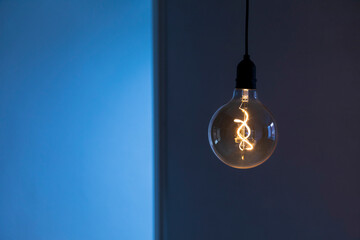 Eingeschaltete Glühbirne hängt in einem dunklen Raum.