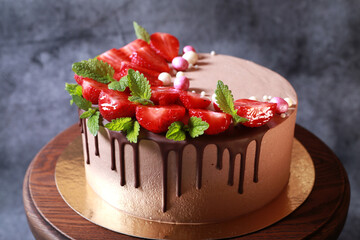 Delicious beautiful cake in chocolate glaze with strawberries and mint
