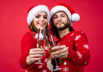 xmas man and woman in knitted sweater and santa hat drink champagme, christmas cheers
