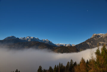 salzachtal Pongau Salzburg gefüllt mit Nebel mit Hagengebirge im Hintergrund unter blau Himmel mit Mond,  Salzach valley filled with fog mountain and blue sky with moon in background