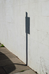 Sign In The Street. Stop sign in the street casting shadow on a white wall on sunny day.