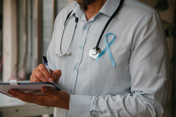 Man doctor holding a blue ribbon, prostate cancer awareness concept. November concept.