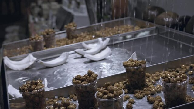 Close-ups of nuts in glasses for sale in the store. Jets of water flow for the freshness of white coconut.