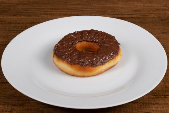 Tasty sweet donuts topped with chocolate and hazelnut cream served on a white plate.