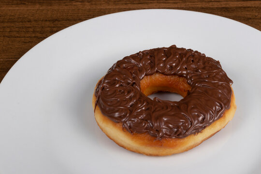 Tasty sweet donuts topped with chocolate and hazelnut cream served on a white plate. Close-up photograph with empty left side for texts.