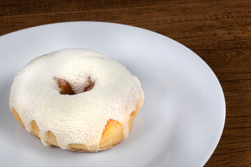 Sweet donuts with cream topping and powdered milk served on a plate. Close-up photo with empty space for texts on the right.