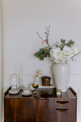 Vintage chest of drawers in a room with a vase and cozy items for the home. Candles and white flowers.