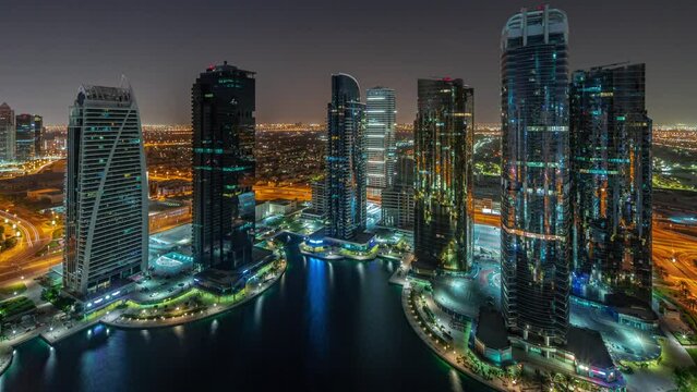 Tall residential buildings at JLT district aerial during all night timelapse, part of the Dubai multi commodities centre mixed-use district panoramic view to towers and skyscrapers