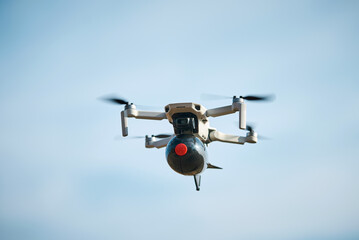 consumer civilian drone with a big bomb on board flies in the blue sky