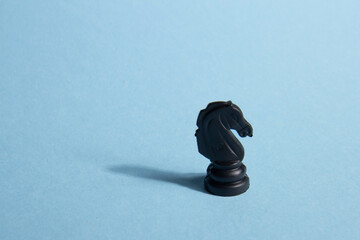 Business and leadership concept. Black chess knight on a blue background
