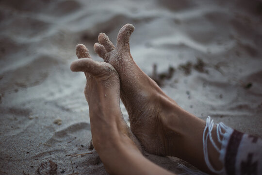 Close up funny feet on sandy beach concept photo. Toes covered with sand. Side view photography with sea coast on background. High quality picture for wallpaper, travel blog, magazine, article