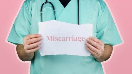 Miscarriage. Doctor with stethoscope in turquoise coat holds note with medical term.