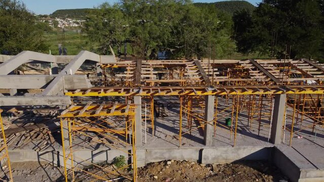 Construction process of reinforced concrete beams and wooden formwork with yellow scaffolding on a sunny day