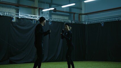Male and female actors wearing motion capture suits performing some fight moves as a game...