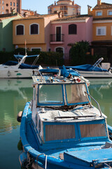 Fototapeta na wymiar Vintage retro boat parked on canal in from of colorful old houses. European relaxing holidays. Colored houses reflected in the water of canal with parked boats