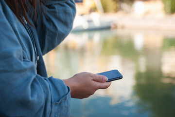 Unrecognizable person using mobile phone close up. Holding smartphone with blurred background with space for text in the right top corner.