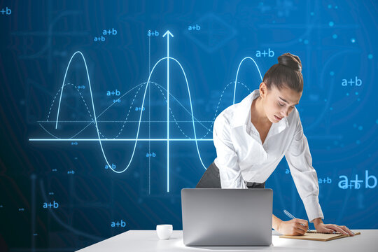 Attractive young european businesswoman leaning on desktop with laptop and writing abstract glowing mathematical formula graph on blue background. Equation, digital data and mathematics app concept.