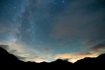 Stars and Milky way visible above mountains in alps, Sauris Italy