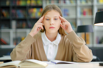 School girl having headache massaging head in class
