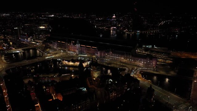 Amsterdam city center skyline by night aerial drone overhead view. Amsterdam Centraal, Ij, Oosterdok, Prins Hendrikkade, public transport, traffic at night. Bright lights urban