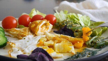 For breakfast, delicious scrambled eggs with vegetables and fresh tomatoes. Breakfast on a keto diet is rich in fats and proteins. Fresh cherry tomatoes are added to the scrambled eggs to add flavor.