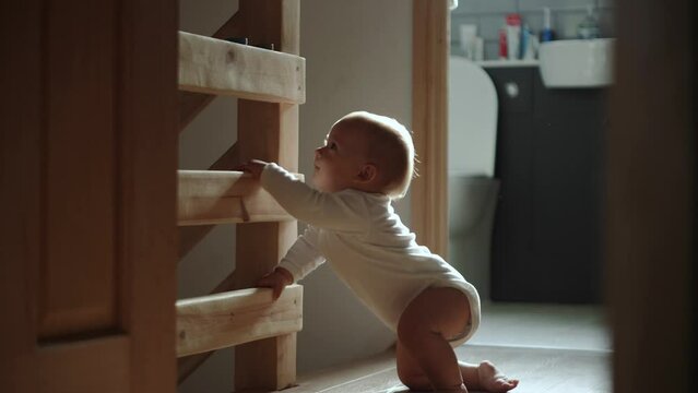 happy baby boy crawling on floor toddler exploring home curious infant having fun enjoying childhood. Little Cute smilling Child in white bodysuit try to stand up walk first steps barefoot on floor