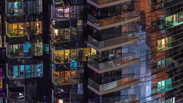 Night view of many glowing windows in apartment residential tower timelapse. High rise illuminated skyscraper with lights in rooms