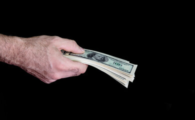 A man holds out a wad of money on a black background